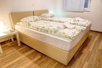 a bed in a bedroom with a wooden floor at Apartment Vita near Terme Paradiso in Dobova