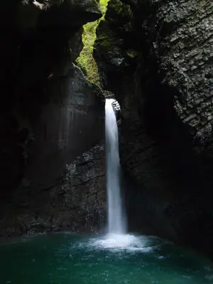 a waterfall in a cave with a pool of water at Apartment Montis Bovec in Bovec