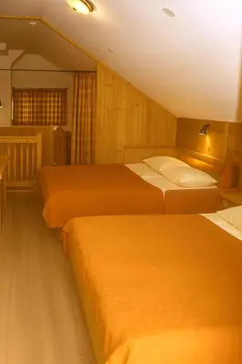 a hotel room with three beds in it at Alpska perla Apartments in Cerkno