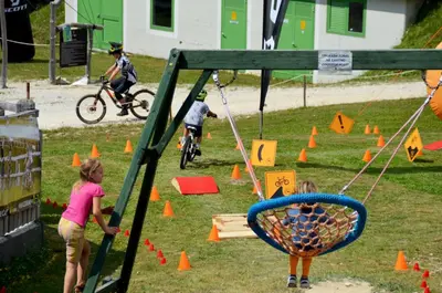 a couple of kids playing on a swing at Alpska perla Apartments in Cerkno