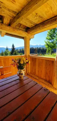 a vase of flowers sitting on a wooden table on a porch at Holiday house Žvan na Pokljuki in Bohinj