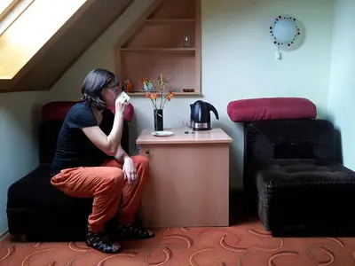 a woman sitting on a chair drinking from a cup at Apartments and rooms Oasis of peace in Bovec