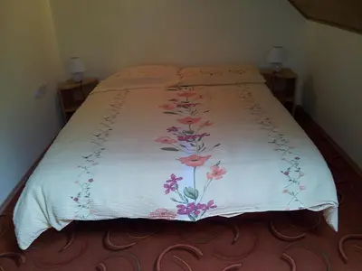 a bed with a white blanket with flowers on it at Apartments and rooms Oasis of peace in Bovec