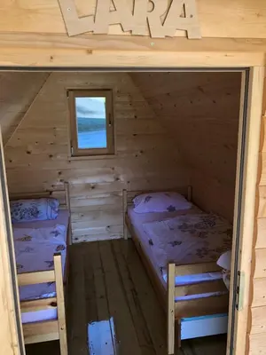 two beds in a wooden cabin with a window at Wooden Cabin Kamna Gorica in Kamna Gorica