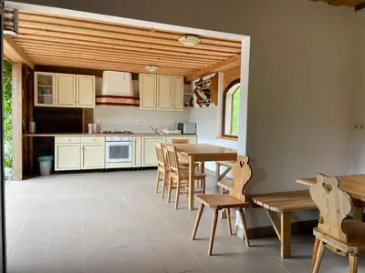a kitchen with white cabinets and a table and chairs at Wooden Cabin Kamna Gorica in Kamna Gorica