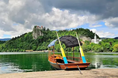 a boat on a dock with a castle in the background at Wooden Cabin Kamna Gorica in Kamna Gorica