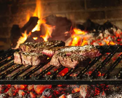 a group of meat on a grill with flames at Penzion Berc in Bled