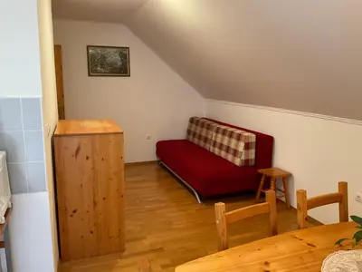 a living room with a red couch and a table at TURISTIČNA KMETIJA STREVC in Solčava