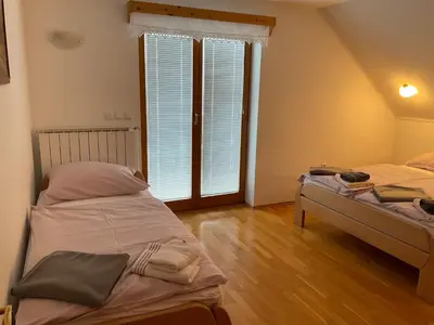 a bedroom with two beds and a large window at TURISTIČNA KMETIJA STREVC in Solčava