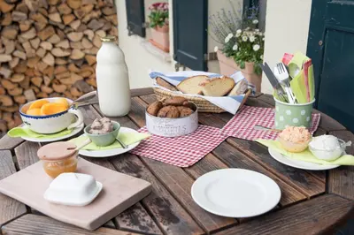 a wooden table with plates of food and milk at Bed & Breakfast Dvorec in Petrovče
