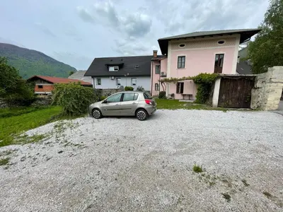 a car parked in a gravel lot in front of a house at Apartment Tina in Bovec