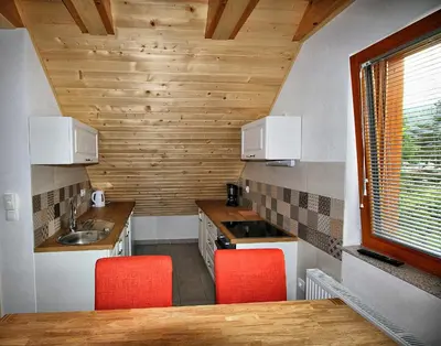 a kitchen with a sink and a counter with red chairs at Apartments Pikon in Bohinj