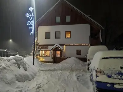 a snow covered house with cars parked in front of it at Apartments Pikon in Bohinj