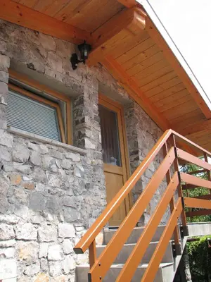 a wooden staircase leading to a stone house with a wooden porch at Apartma Furlan in Štanjel