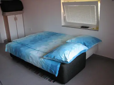a bedroom with a bed with blue sheets and a window at Apartma Furlan in Štanjel