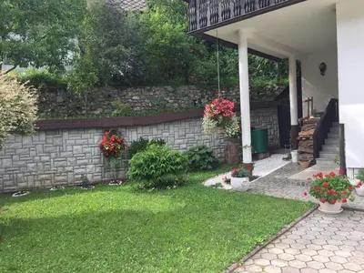 a backyard with a stone retaining wall and flowers at Kirhouse Apartment in Bohinjska Bela