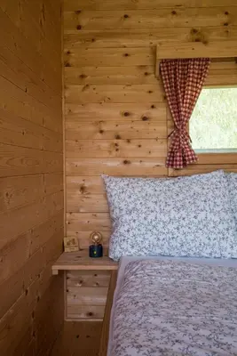 a bedroom with a bed with a wooden wall at Mountain view Glamping in Dovje