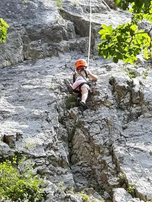 a person in an orange helmet climbing a rocky mountain at Apartment Beautiful Črni Kal in Črni Kal