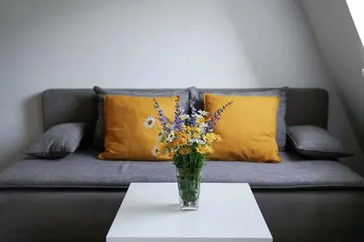 a vase of flowers on a table in front of a couch at Apartment Alpea in Bovec