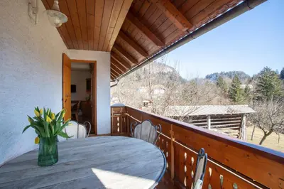 a wooden table on a balcony with a vase of flowers at Holiday Lake in Bled