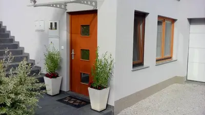 an orange door with two potted plants on the side of a house at Apartment Visak in Bled