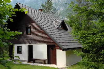 a house with a gambrel roof with a bench in front at Apartmaji Zupančič in Bohinj
