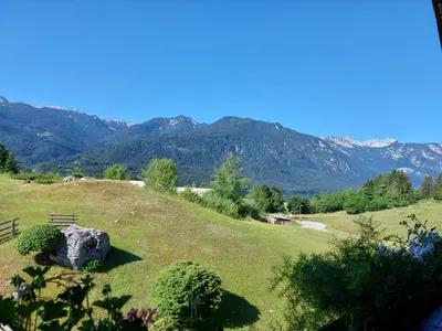 a grassy hill with a fence and mountains in the background at Apartmaji Vesna in Bohinj