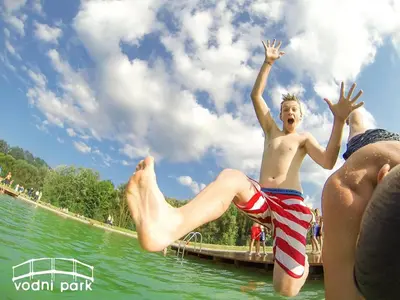 two young boys jumping into the water at a lake at Green Resort Glamping in Radlje ob Dravi