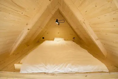 a bed in a wooden cabin with a light on it at Green Resort Glamping in Radlje ob Dravi