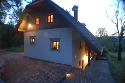 a white house with lights in the windows at Chalet ApArt Kupljenik 12 A, Bled in Bohinjska Bela