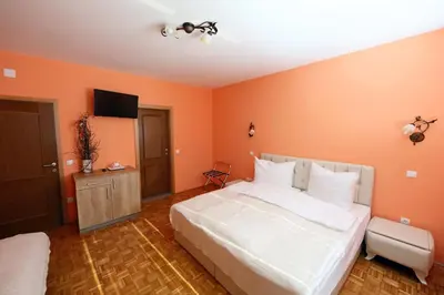 a bedroom with a large white bed with orange walls at Sobe Grabar in Ptuj