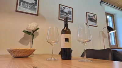 a bottle of wine sitting on a table with two wine glasses at ecoHouse FURLAN - Apartment PINJA in Kobarid
