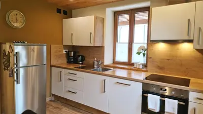 a kitchen with white cabinets and a stainless steel refrigerator at ecoHouse FURLAN - Apartment PINJA in Kobarid