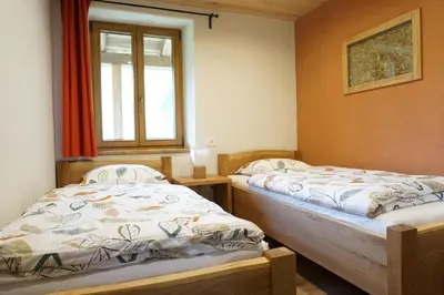 two twin beds in a room with a window at ecoHouse FURLAN - Apartment PINJA in Kobarid