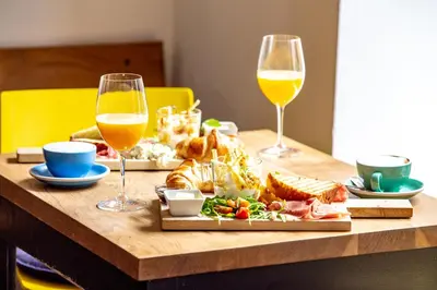 a table with two glasses of wine and a plate of food at Isabella Living in Maribor