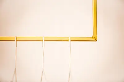 a mirror hanging on a white wall with strings at Isabella Living in Maribor