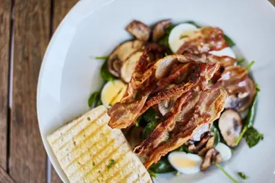 a white plate of food with meat and vegetables at Isabella Living in Maribor