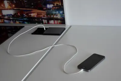 a black cell phone sitting on a white desk at Studio Optim in Ljubljana