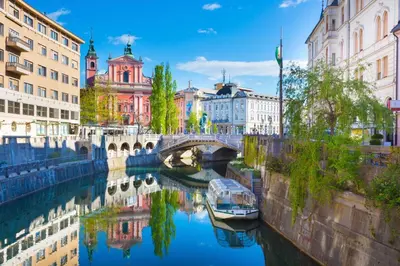 a river with a bridge and a boat in the water at Studio Optim in Ljubljana