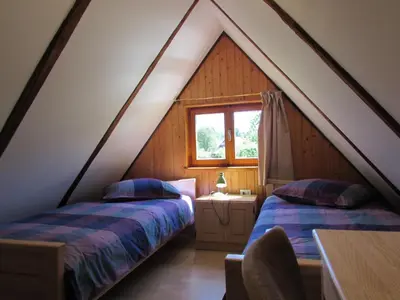 a attic bedroom with two beds and a window at Apartma Narnia in Bovec