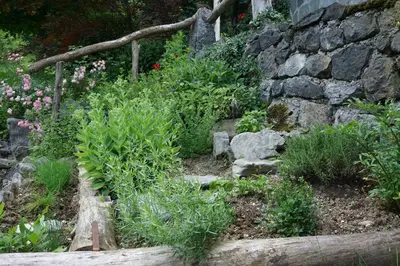 a garden with flowers and a stone wall at Slabnik Nature Escape in Idrija