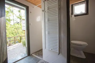 a bathroom with a toilet and a sliding glass door at Slabnik Nature Escape in Idrija