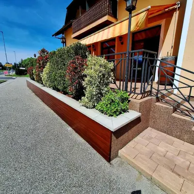 a building with a row of plants in front of it at Penzion Gostisce Lesjak in Orehova vas
