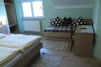 a bedroom with two beds and a table and a bench at Penzion Gostisce Lesjak in Orehova vas