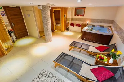 a room with a tub and a table and chairs at Villa Aina Boutique Hotel in Laško