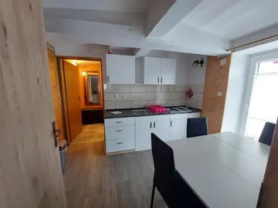 a kitchen with white cabinets and a table with chairs at Apartment Carli-Jurč in Kobarid
