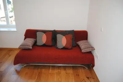 a red couch with several pillows on it at Apartment with Free Parking in Ljubljana