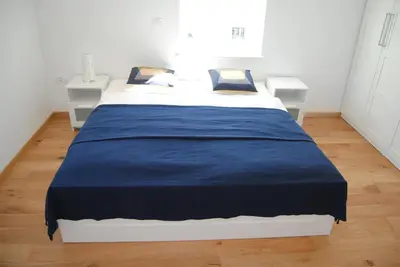 a large bed in a room with two white tables at Apartment with Free Parking in Ljubljana
