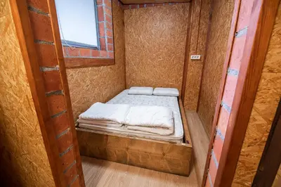 a small bed in a wooden room with a window at Hostel Paradiso in Tolmin