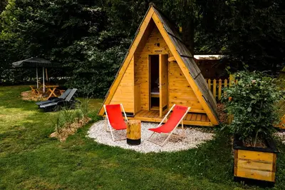 a wooden cabin with two red chairs in front of it at Glamping FOREST EDGE in Kamnik
